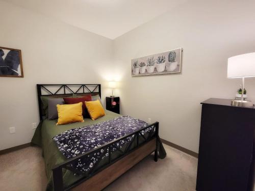 a bedroom with a bed with yellow pillows on it at Brand New 2 Bedroom Apartment Steps from Mayo! in Rochester
