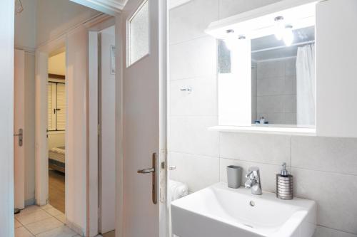 a white bathroom with a sink and a mirror at Apartment @Katehaki Metro in Athens