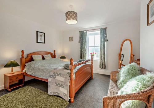a bedroom with a bed and a chair and a window at Pear Tree Cottage - Solway Coast in Bowness-on-Solway