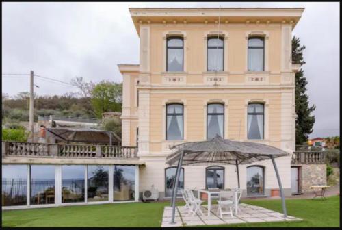 een groot huis met een tafel en een paraplu bij Villa Le Palme Swimming-Pool & Relax in the Gulf of Poets in La Spezia