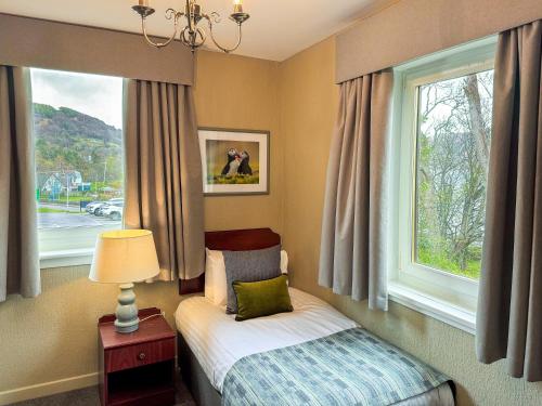 een kleine slaapkamer met een bed en een raam bij The Royal Hotel in Ullapool