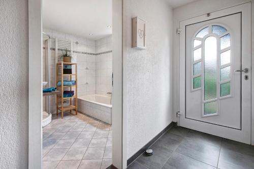 a bathroom with a white door and a bath tub at Fernblick in Weilheim