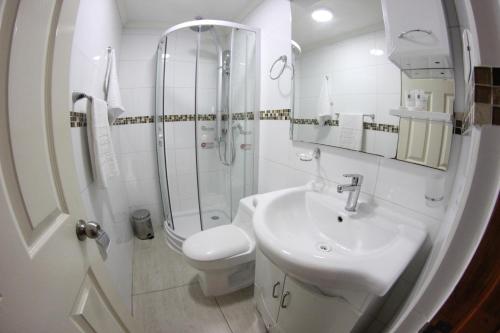 a white bathroom with a toilet and a sink at HOTEL QUINTA ESTACIÓN in Caldera