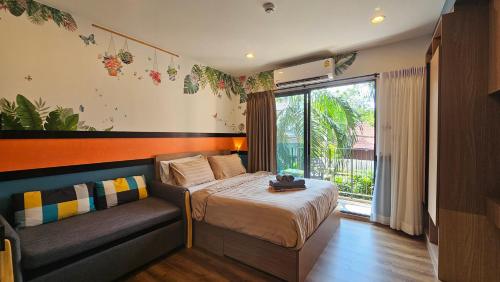 a bedroom with a bed and a couch and a window at La Habana HuaHin by ABCD in Hua Hin