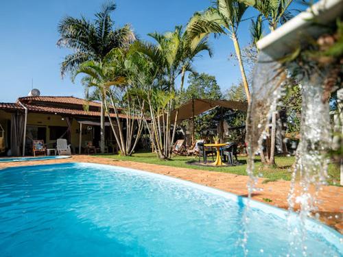 a swimming pool with a fountain in front of a house at Pousada Confraria Casa Branca in Casa Branca