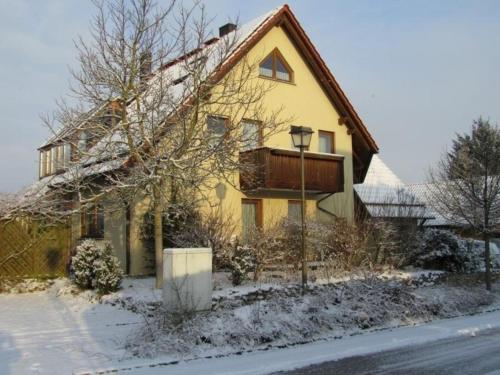 a yellow house with snow on the ground at Komfortable Ferienwohnung in Ebensfeld mit Garten und Grill in Ebensfeld