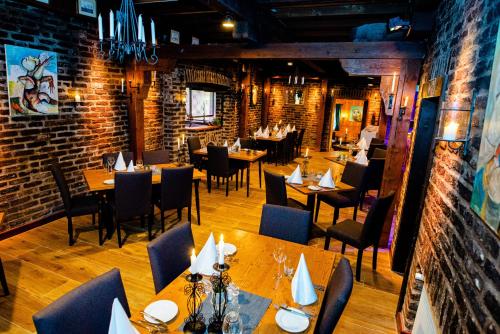 a restaurant with wooden tables and chairs and brick walls at Landgasthaus Steinsmühle in Bad Münstereifel