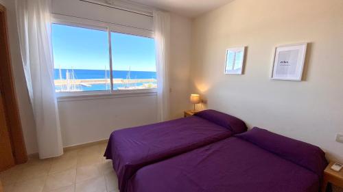 ein Schlafzimmer mit einem lila Bett und einem Fenster in der Unterkunft RMP 32 Residencial Marina del Port in L'Ametlla de Mar