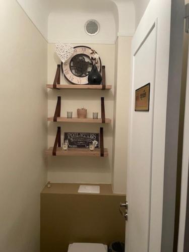 La salle de bains est pourvue de toilettes et d'une horloge murale. dans l'établissement Cosy appartement proche de Paris, à Le Raincy