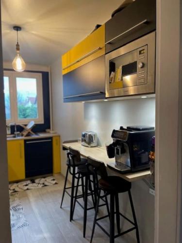 une cuisine avec une table avec des chaises et un micro-ondes dans l'établissement Cosy appartement proche de Paris, à Le Raincy