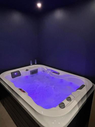 un grand bain à remous avec de l'eau violette dans une pièce dans l'établissement « Bulles de Bonheur », à Cherbourg en Cotentin