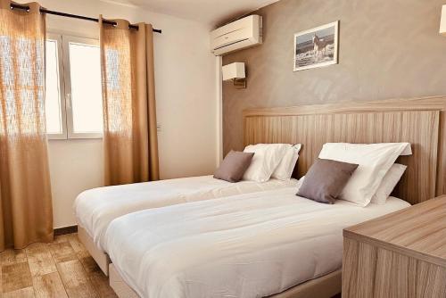 - 2 lits dans une chambre d'hôtel avec fenêtre dans l'établissement Hotel Les Palmiers En Camargue, à Saintes-Maries-de-la-Mer