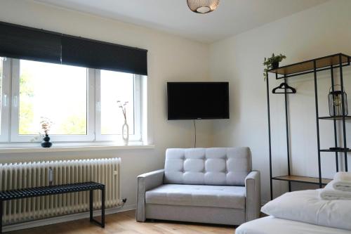 sala de estar con silla y TV en City Apartment in bester Lage, en Wolfsburg