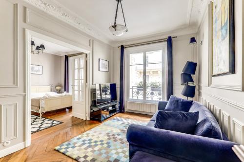 a living room with a blue couch and a tv at Appartement charmant Quartier culturel in Paris