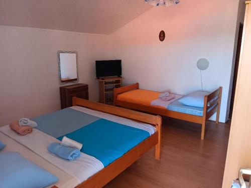 a small room with two beds and a television at Apartmani Ivan in Gornji Karin