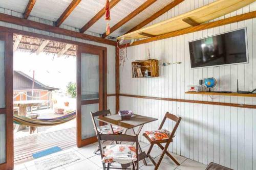 a patio with a table and two chairs and a television at Toca da Garoupa in Laguna
