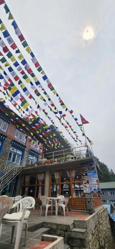Phakding的住宿－Shangri-la Guest House，一座有五颜六色旗帜的建筑,桌子和椅子