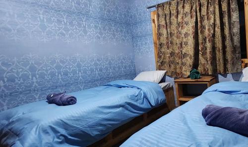 1 dormitorio con 2 camas individuales y sábanas azules en Shangri-la Guest House, en Phakding