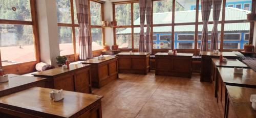 une grande chambre avec des tables en bois et un train dans l'établissement Shangri-la Guest House, à Phakding