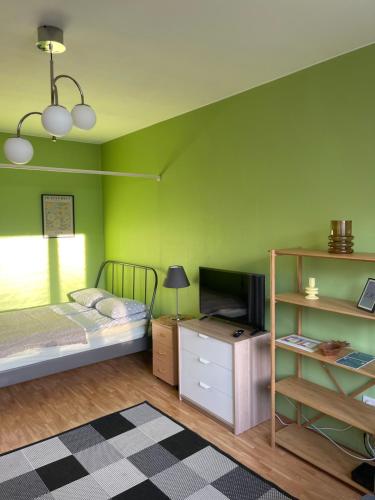 a bedroom with green walls and a bed and a tv at The Golden Glow Apartment Turku in Turku