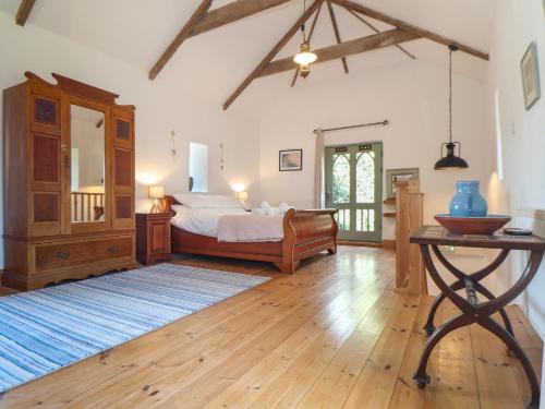 a bedroom with a bed and a table in it at Oofoos Barn in Helston
