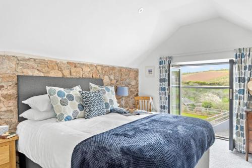 ペイントンにあるThe Dairy, Higher Yalberton Farmのベッドと石の壁のある寝室