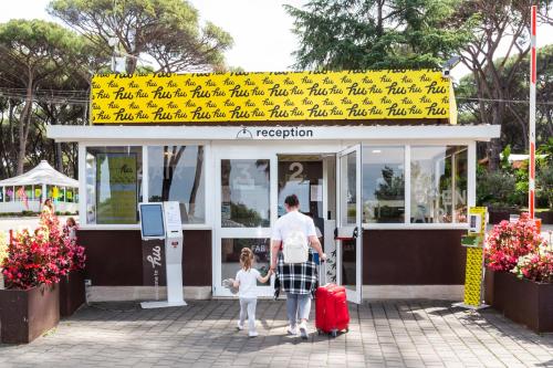 a man and a little girl with luggage in front of a shop at Fabulous village in Casal Palocco