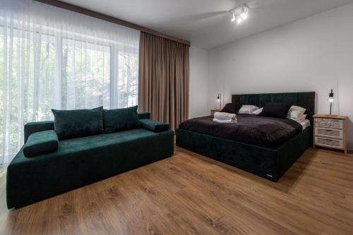 a bedroom with a bed and a green couch at Apartamenty Cicha - bezpłatny parking in Krynica Zdrój