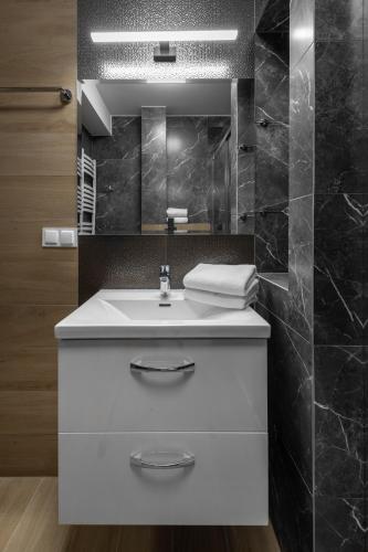 a bathroom with a white sink and a mirror at Apartamenty Cicha - bezpłatny parking in Krynica Zdrój