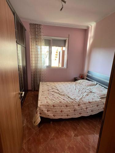 een slaapkamer met een bed en een raam bij Lindi's Guest House in Kamëz