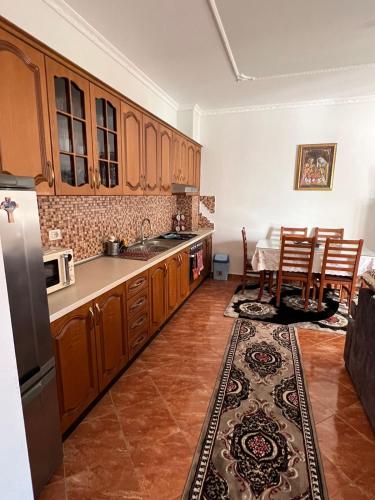 een keuken met houten kasten en een tafel en stoelen bij Lindi's Guest House in Kamëz