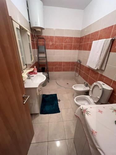 een badkamer met een toilet, een wastafel en een spiegel bij Lindi's Guest House in Kamëz