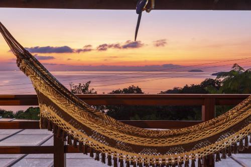 a hammock on a deck with a sunset in the background at Pousada Recanto de Paraty in Paraty