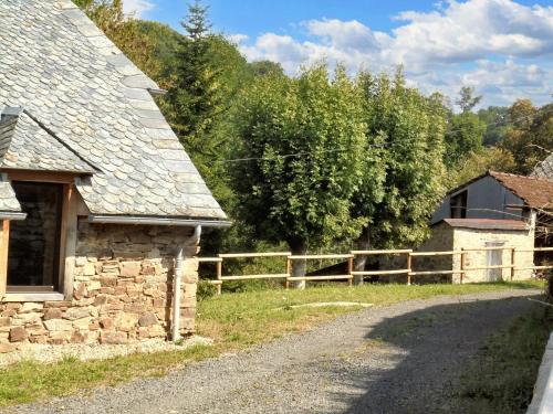 an old stone house with a fence on a road at Maison spacieuse à Castelnau-de-Mandailles avec cheminée 250 m² in Castelnau-de-Mandailles