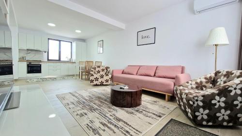 un soggiorno con divano rosa e sedie di X rent apartment a Prim Decembrie