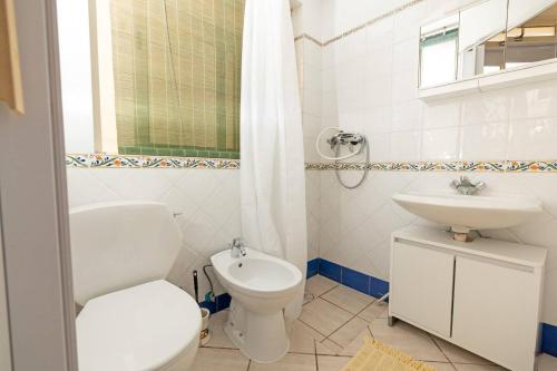 a white bathroom with a toilet and a sink at Ghadirabay Seafront With Sea Views By Homely in Mellieħa