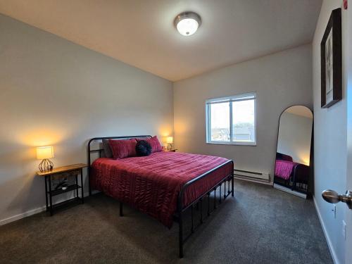 a bedroom with a bed with a red comforter and a window at HUGE Apartment, 2 Bedroom, 2 Bathroom, Park Free in Rochester