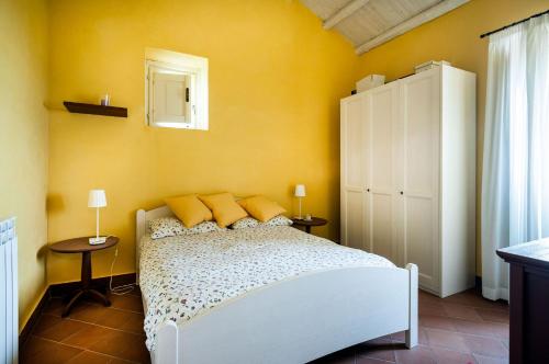Un dormitorio con una cama blanca con paredes amarillas en Villa Eremo Sant'Emilia, en Trecastagni