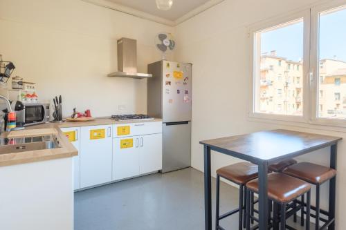 a kitchen with a table and a refrigerator at Ostello Umile in Bologna