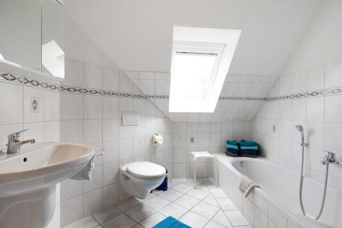 a white bathroom with a toilet and a tub and a sink at Ferienwohnung Nico in Langballig