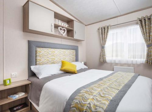 a bedroom with a large bed with a yellow pillow at SBL38 Caravan at Camber Sands - quiet location in Camber