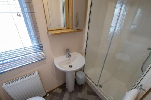 y baño con lavabo y ducha. en SBL38 Caravan at Camber Sands - quiet location en Camber