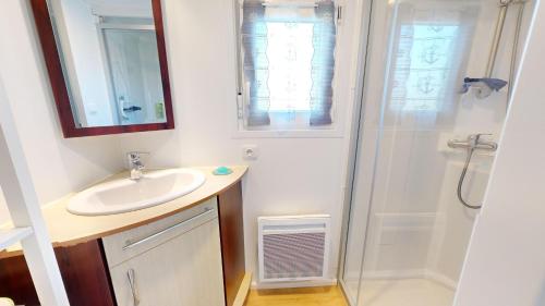 uma casa de banho com um lavatório e um chuveiro em Posadom, Mobil Home 82 avec piscine em Brem Sur Mer