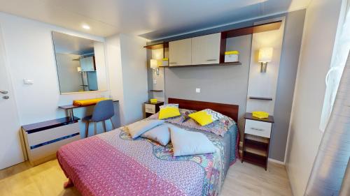 um pequeno quarto com uma cama e uma secretária em Posadom, Mobil Home 82 avec piscine em Brem Sur Mer