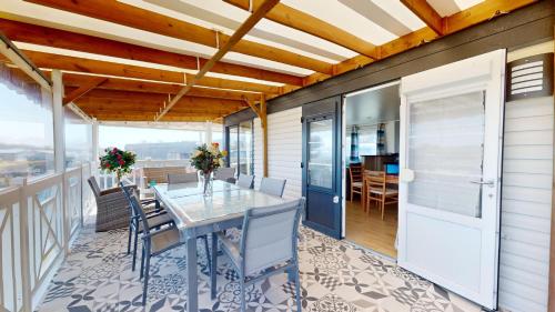 une salle à manger avec une table et des chaises sur un balcon dans l'établissement Posadom, Mobil Home 82 avec piscine, à Brem-sur-Mer