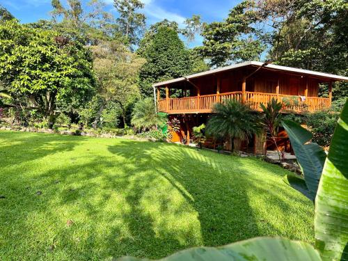 une grande cour avec une maison dotée d'une terrasse en bois dans l'établissement Mineral River Eco Village, à Upala