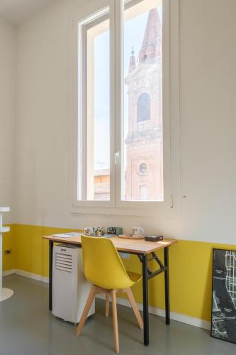 a desk with a yellow chair and a window at Ostello Umile in Bologna