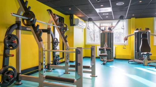 Thon Hotel Europa في أوسلو: صالة ألعاب رياضية مع العديد من آلات المشي في غرفة صفراء