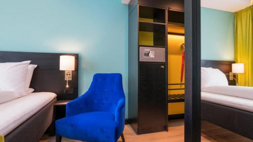 オスロにあるThon Hotel Europaの青い椅子とベッドが備わるホテルルームです。