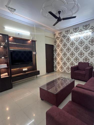 Kashi Anadam HomeStay في فاراناسي: غرفة معيشة مع أريكة وتلفزيون كبير
